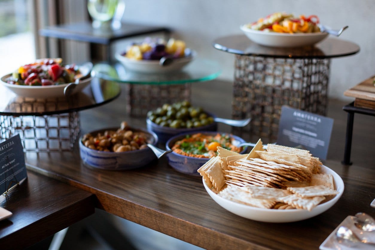 Grazing station with salads, olives, hummus and crackers on tiered stands