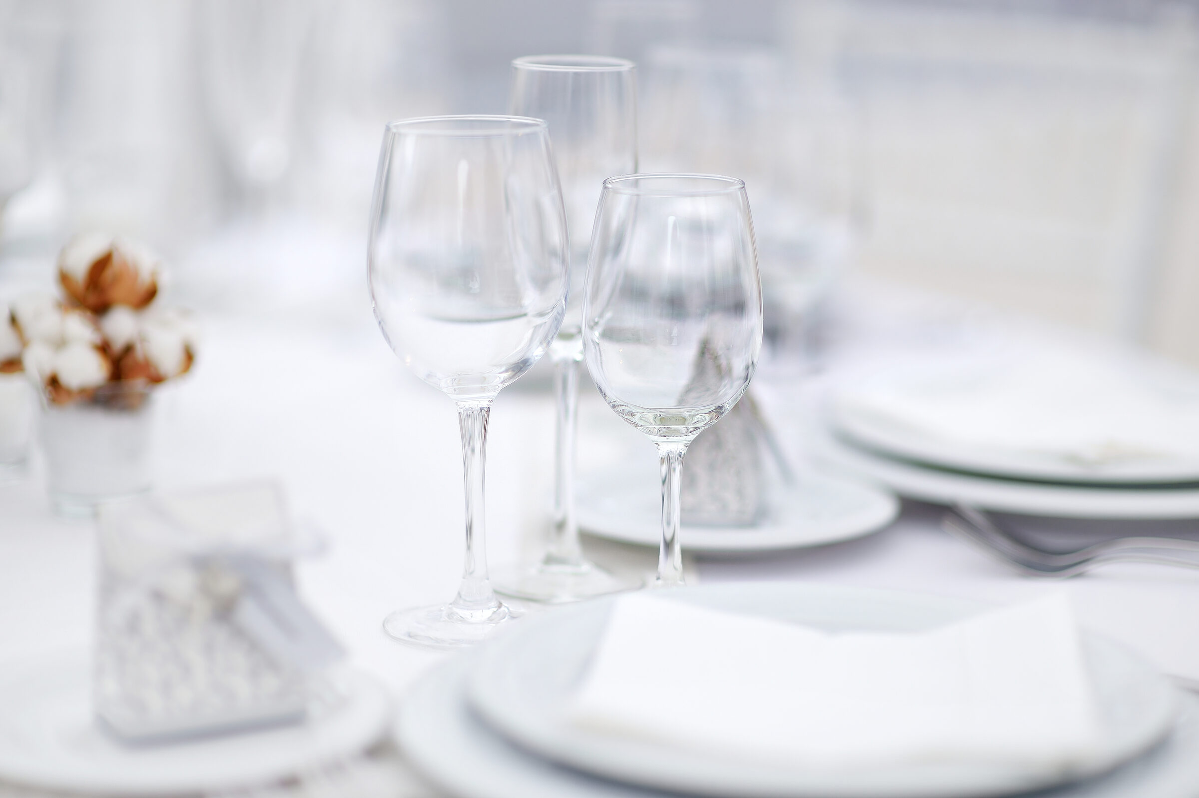 Table set with polished glassware, white china and linen