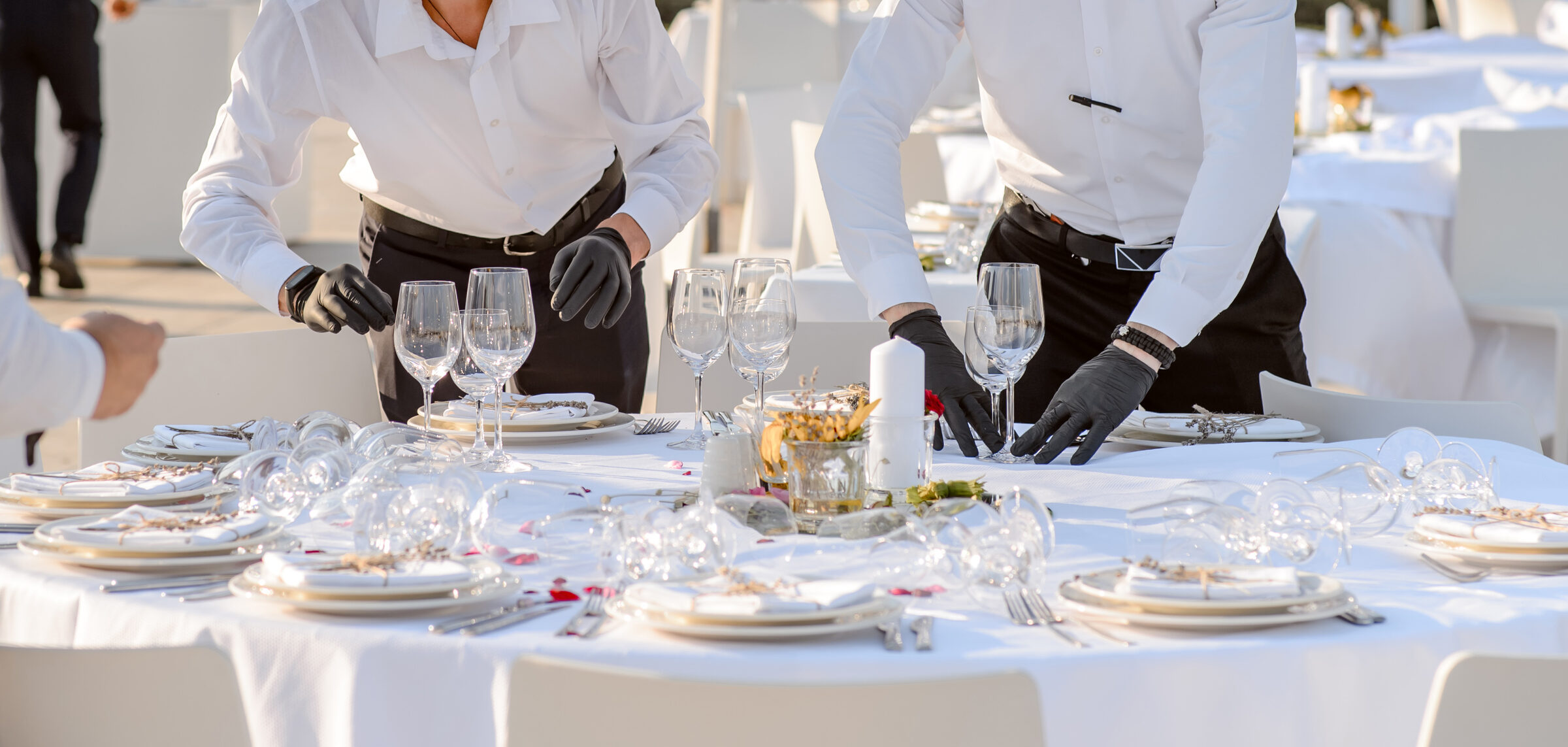 Service staff setting a round event table with glassware
