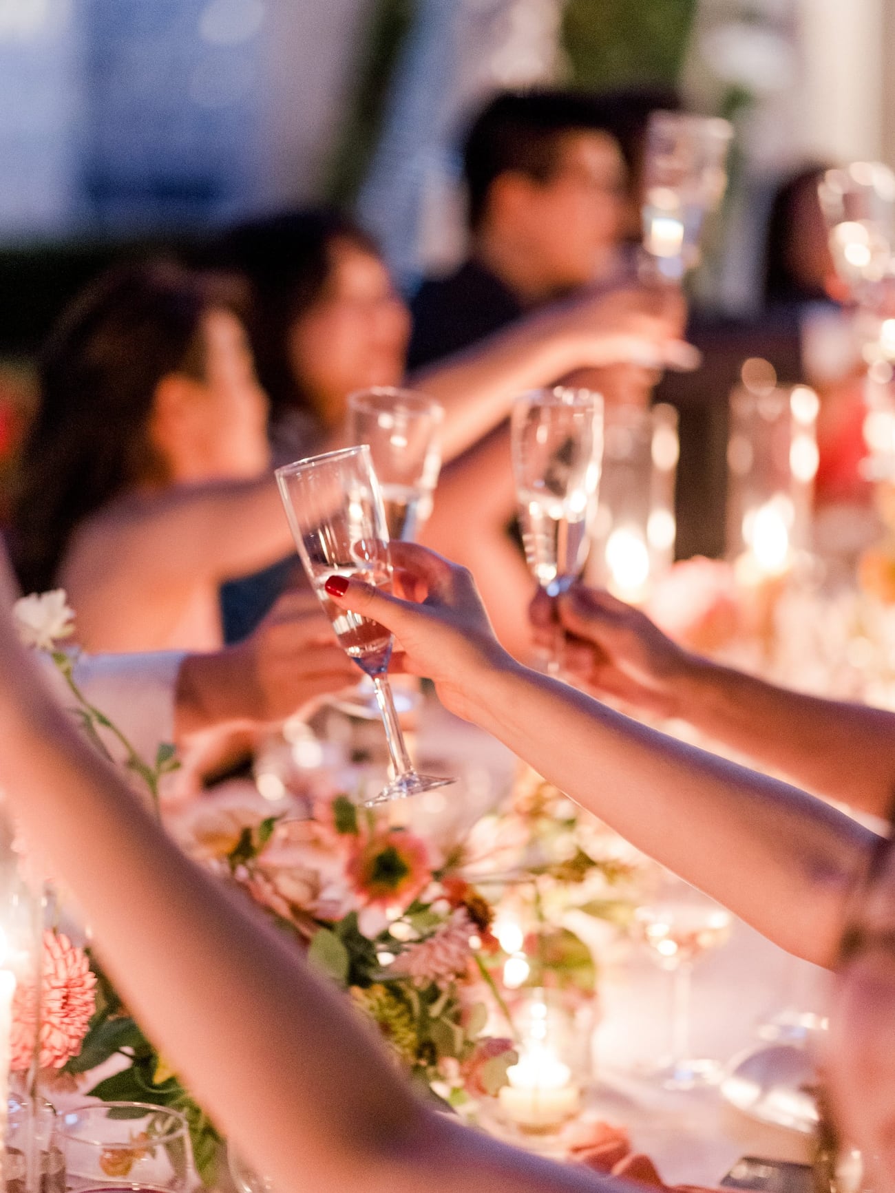 Guests raising glasses in a candlelit champagne toast